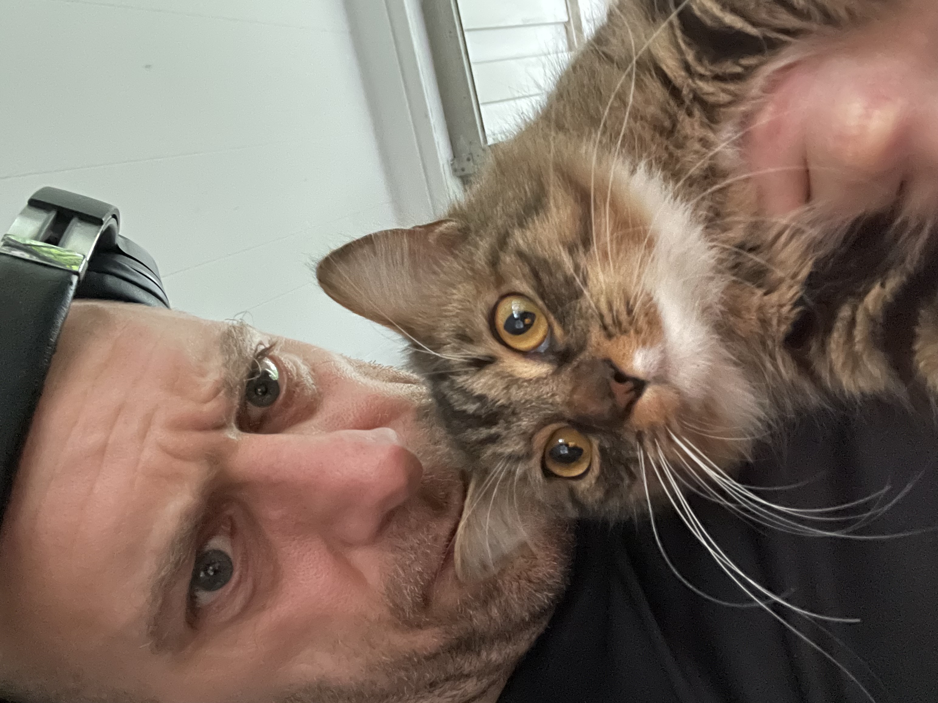 Eric in a close selfie with Lucky, a tabby cat.